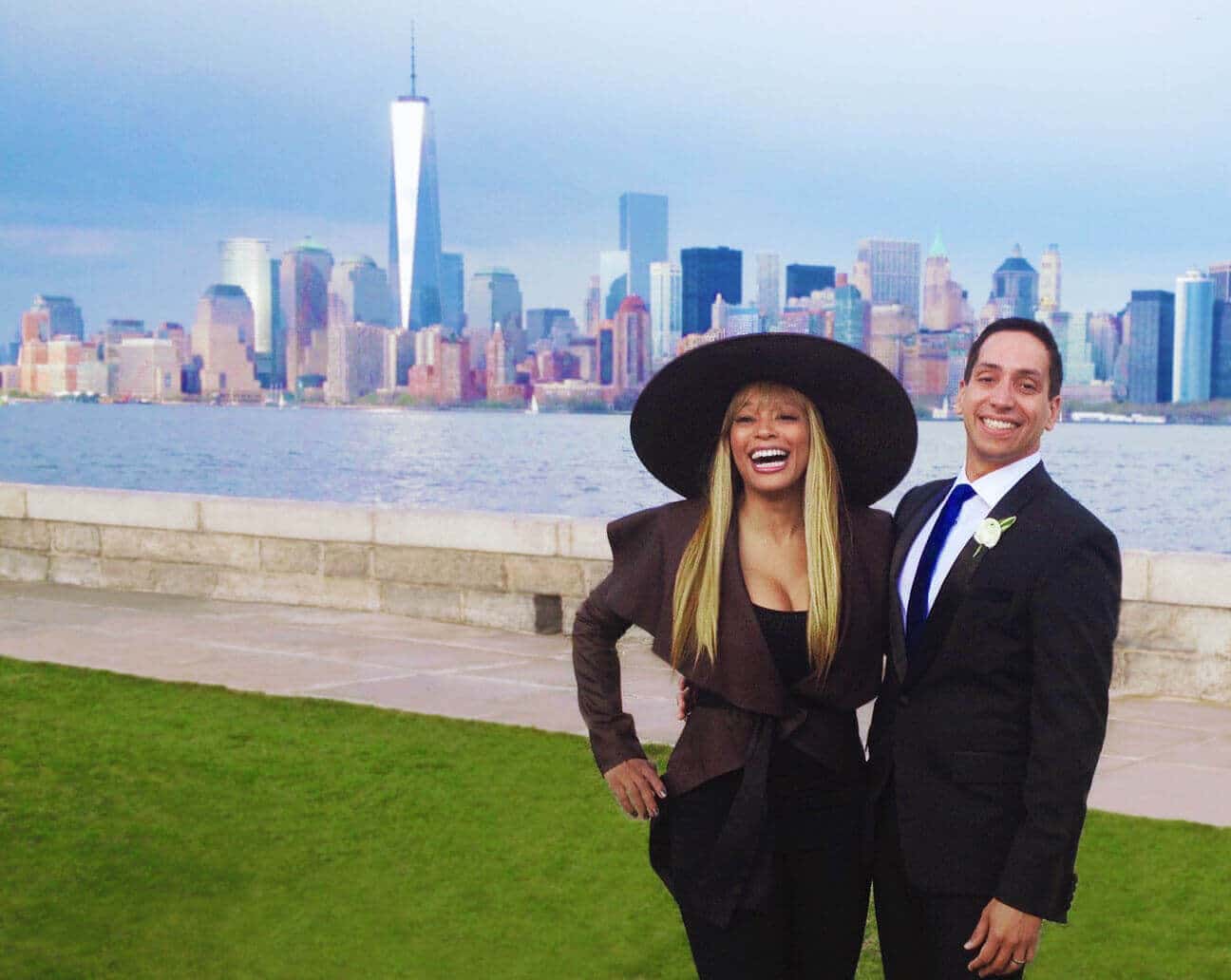 Kwanza Jones and Jose E Feliciano pose smiling against New York skyline